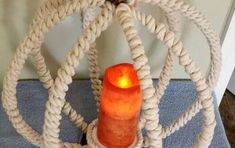 an orange candle sitting on top of a white wicker basket with rope wrapped around it