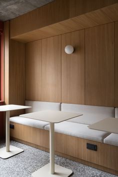 two white tables sitting next to each other on top of a carpeted floor in front of a window