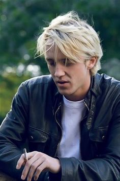 a young man with blonde hair wearing a black leather jacket and white t - shirt