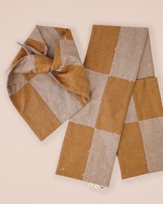 two pieces of cloth are laying next to each other on a white surface with a brown and tan checkered design