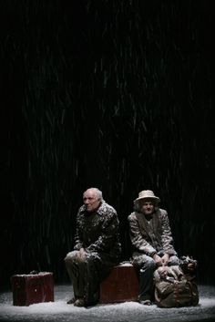 two people sitting on suitcases in the snow