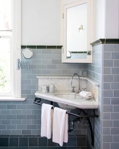 a white sink sitting under a window in a bathroom