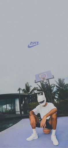 a man sitting on top of a basketball court next to a net with a sky background