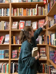 a woman is pointing at books on a book shelf