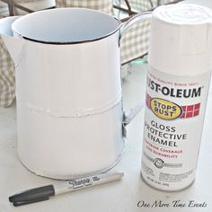 a white paint can sitting on top of a table next to a cup and brush