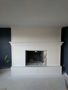 an empty room with a white fireplace and blue walls