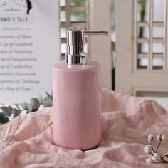 a pink soap dispenser sitting on top of a bed