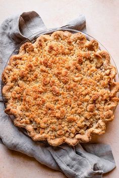 a pie sitting on top of a table next to a gray cloth and a wooden spoon