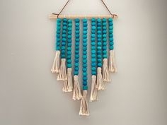 a blue beaded wall hanging with tassels and beads on a white background