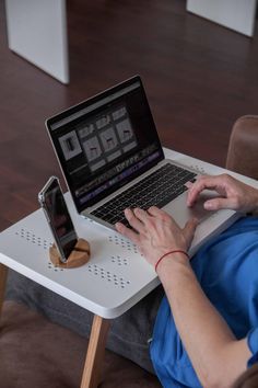 a woman sitting at a table with a laptop and cell phone on her lap top