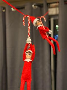 two elfs hanging from a rope with candy cane