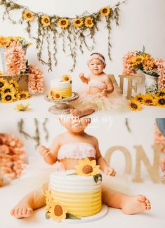 a baby sitting in front of a cake with sunflowers on the top and bottom