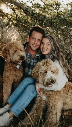 a man and woman sitting next to two dogs