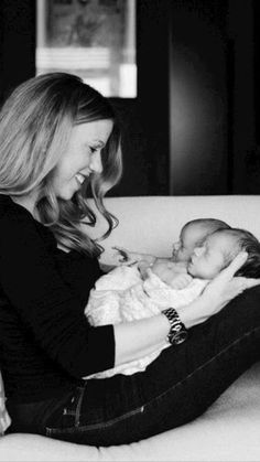 a woman sitting on top of a couch holding a baby