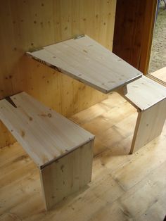 two wooden benches sitting next to each other on top of a hard wood floor in front of a window