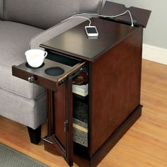 a small table with a phone on it and a coffee cup in the bottom drawer