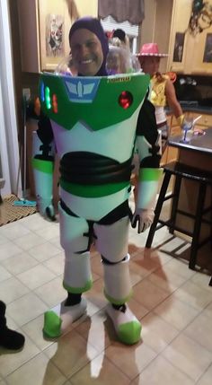 a young boy dressed up as buzz lightyear from the movie toy story, standing in a kitchen