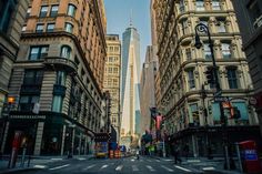 an empty city street with tall buildings on both sides and people walking in the middle