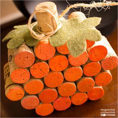 an orange wine cork decoration with leaves on the top, sitting on a wooden table