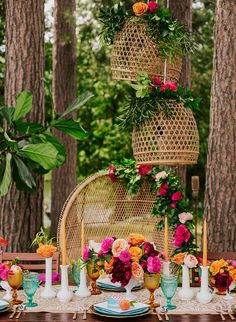 the table is set with colorful flowers and greenery hanging from the ceiling, along with candles