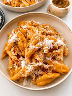 two bowls filled with pasta covered in parmesan cheese