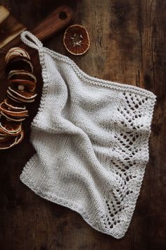 a white knitted dishcloth next to some slices of fruit on a wooden table