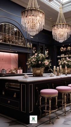 an elegant kitchen with chandeliers and pink stools in front of the bar