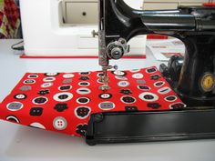 a sewing machine with a red and black cloth on it's side next to a white table