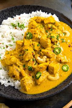 a black bowl filled with rice and chicken curry