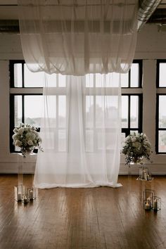 an empty room with candles and flowers in vases on the floor next to large windows