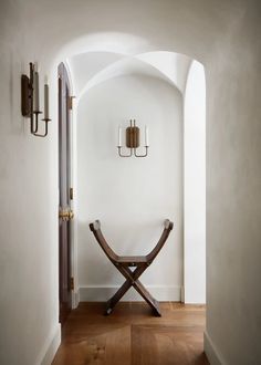 a wooden bench sitting in the middle of a hallway next to a doorway with two lights on either side