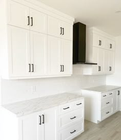 an empty kitchen with white cabinets and marble counter tops in the middle of the room