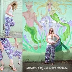 a woman standing in front of a wall with mermaids on it's side