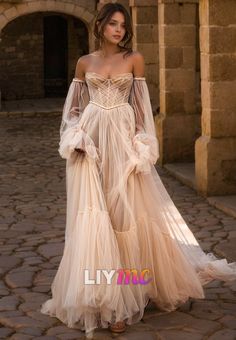 a woman in a long dress standing on a cobblestone street wearing an off the shoulder gown