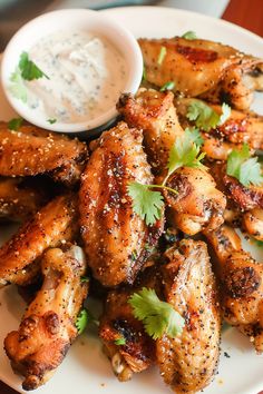 chicken wings on a plate with ranch dressing and garnished with cilantro