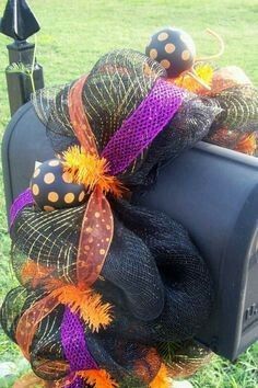 a black mailbox decorated with orange and purple mesh, pumpkins and polka dots