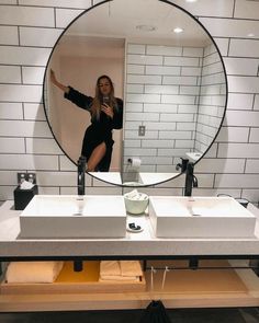 a woman taking a selfie in front of a bathroom mirror with her arms out