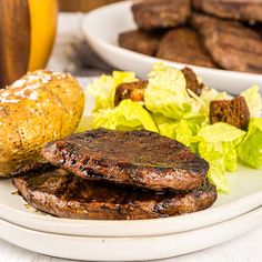 two hamburgers on a plate with lettuce and some other foods in the background