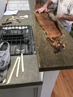 a man standing in front of a stove top oven next to a counter with tools on it