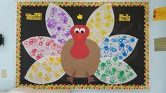 a turkey made out of handprints on a bulletin board in a classroom setting