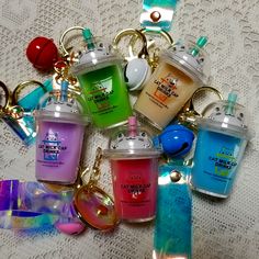 many small bottles are sitting on a table with keychains around them that have charms attached to them