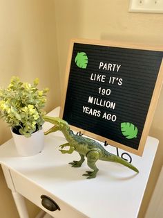 a toy lizard sitting on top of a table next to a sign that says party like it's 150 million years ago