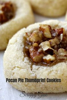 pecan pie thumbprint cookies with walnuts in the middle on a white surface