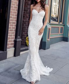 a woman in a wedding dress standing on the sidewalk