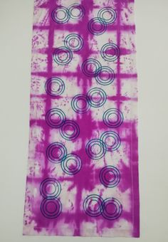 a purple and blue tie - dyed towel with circles on it, hanging from the wall