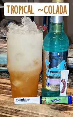 a bottle of alcohol sitting on top of a wooden table next to a glass filled with ice