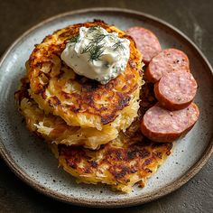 a plate topped with pancakes and sausages on top of a wooden table next to a fork