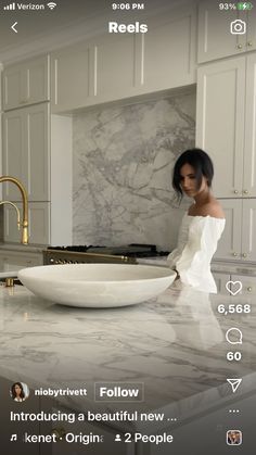 a woman standing in front of a white bowl on top of a kitchen counter next to a sink