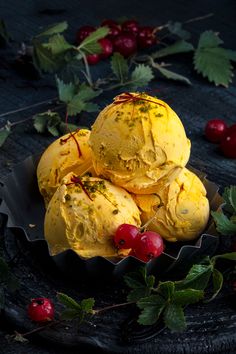 three scoops of ice cream with cherries and leaves on a plate next to berries