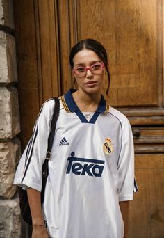 a woman with glasses standing in front of a wooden door